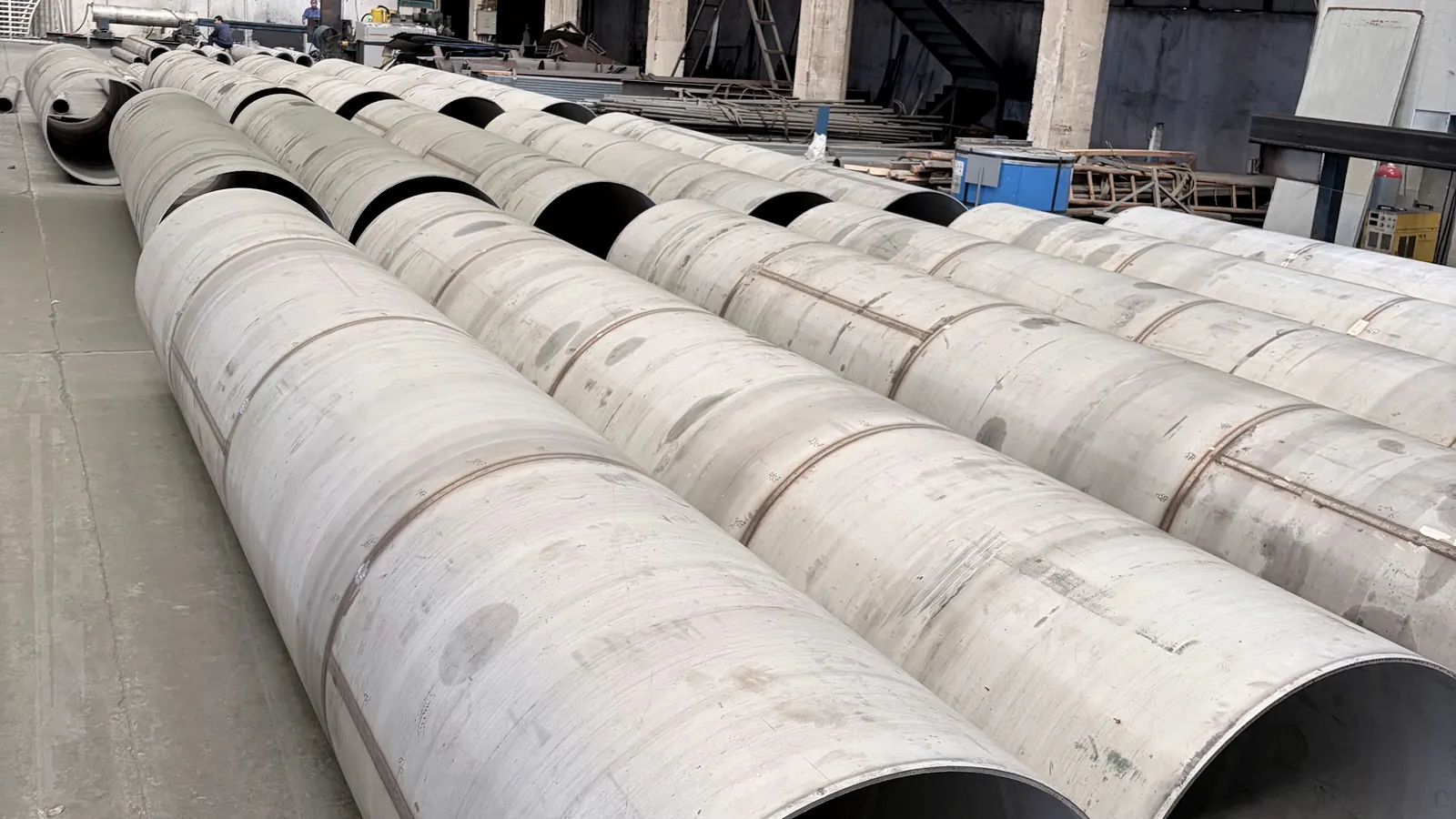 Large-diameter stainless steel welded pipe sections on a factory floor